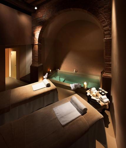 a bathroom with a tub and a bed and a table at Il Borro Relais & Châteaux in San Giustino Valdarno