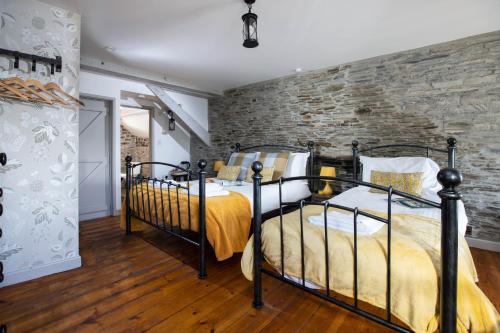 a bedroom with a bed with a brick wall at The Olde Malthouse Inn in Tintagel