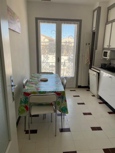 a kitchen with a table with chairs and a window at Appartement proche du canal du midi in Colombiers