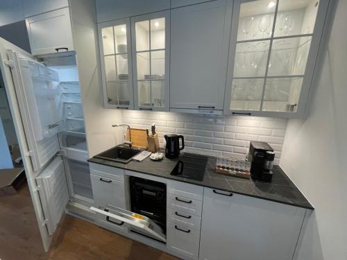 a kitchen with white cabinets and an open refrigerator at PINEA Apartments Pobierowo z niesamowitym widokiem na morze oraz jacuzzi w wybranych apartamentach in Pobierowo