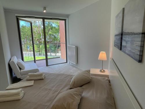 a bedroom with a bed and a chair and a window at PINEA Apartments Pobierowo z niesamowitym widokiem na morze oraz jacuzzi w wybranych apartamentach in Pobierowo