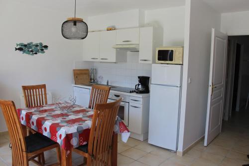 eine Küche mit einem Tisch und einem weißen Kühlschrank in der Unterkunft APPARTEMENT LES PINS PENCHES Hardelot plage in Neufchâtel-Hardelot