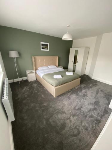 a bedroom with a bed and a green wall at Bridlington Shore Apartment in Bridlington