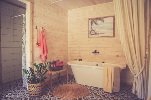 un bagno con vasca bianca in una parete in legno di Hellamaa Retrovisiit Alma & Vilma a Hellamaa