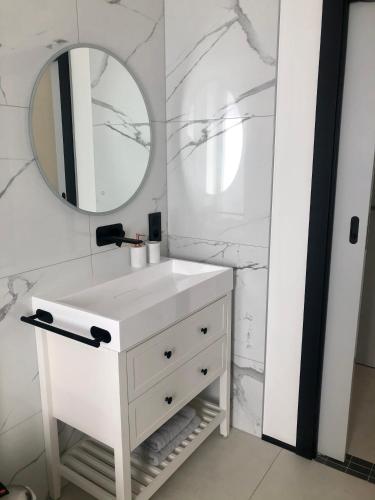 uma casa de banho branca com um lavatório e um espelho em Studio calme-équipements haut de gamme em Sarreguemines