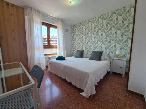 a bedroom with a white bed with a green wall at Espacioso apartamento con impresionantes vistas y garaje privado - Dos Torres Tauriel in Zaragoza