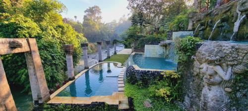 a swimming pool with a waterfall next to a river at Avalon Ubud Castle & SPA in Ubud