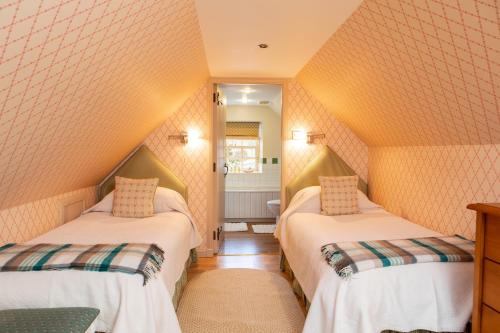 2 camas en una habitación pequeña con paredes de color naranja en Balnagown Estates Gardener's Cottage, en Kildary
