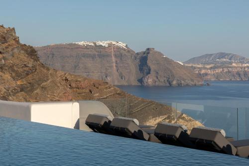 a swimming pool with chairs and a view of the water at Hom Santorini in Oia