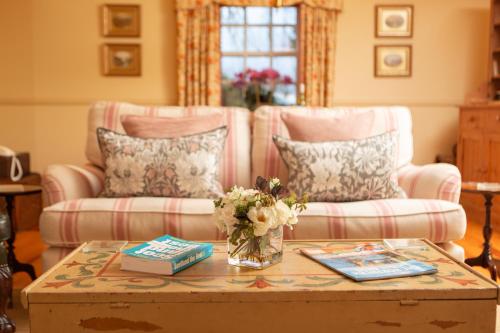 ein Wohnzimmer mit einer Couch und einem Tisch mit Blumen in der Unterkunft Balnagown Estates Gardener's Cottage in Kildary