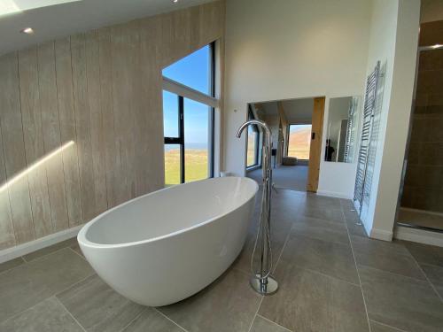 a white tub in a bathroom with a large window at 5 Bedroom Cottage - Llyn Peninsula in Pistyll