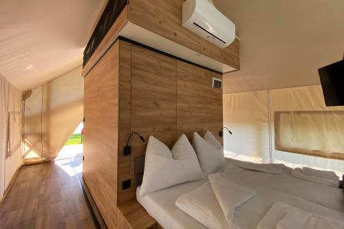 una camera da letto con un grande letto bianco e una parete in legno di Comfort Safarizelt direkt am Ossiachersee a Steindorf am Ossiacher See
