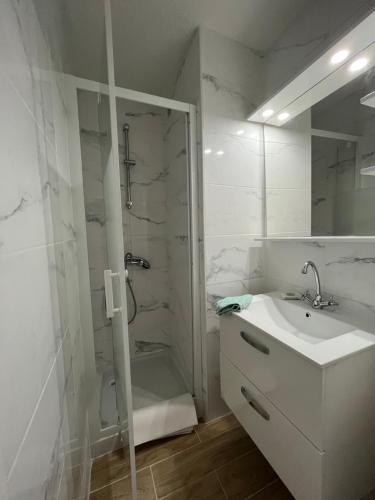 une salle de bain blanche avec une douche et un lavabo dans l'établissement Appartement 2 pièces en rez de jardin avec parking et piscine, à Villeneuve-Loubet