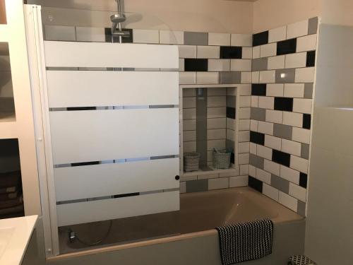 La salle de bains est pourvue d'une baignoire et de carrelage noir et blanc. dans l'établissement Gîte Le Meynet, à Saint-Cyprien