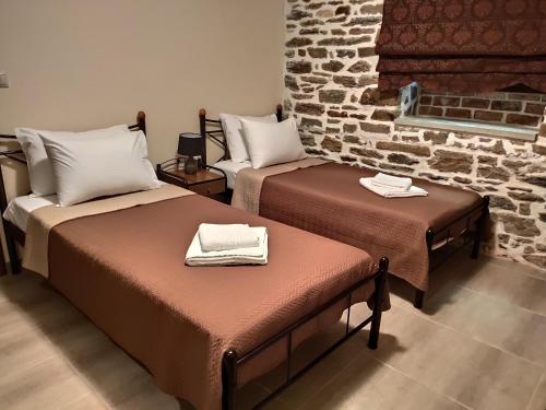 a room with two beds and a brick wall at KERAMIDI GUESTHOUSE in Keramídhion