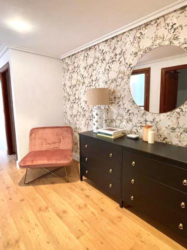 a bedroom with a dresser and a mirror and a chair at El Maltés in Cudillero