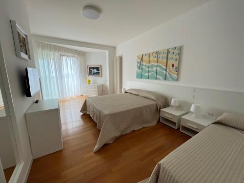 1 dormitorio con 2 camas y TV. en Appartamenti Aquamarina en Lido di Jesolo