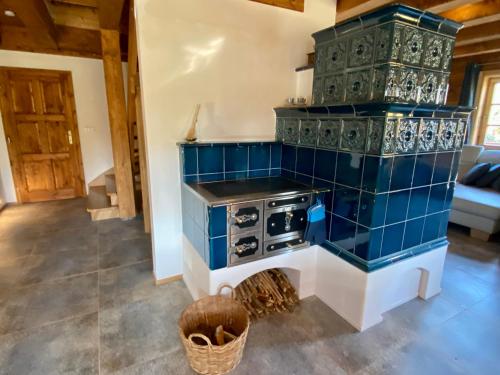 a kitchen with a stove and a blue tiled wall at Roubenka Kamennka in Borotín