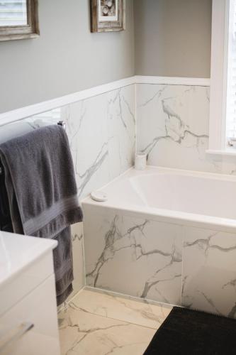 a bathroom with a white tub and marble tiles at Large Country House with Hot Tub, Pool Table, and Log Burner in Three Legged Cross