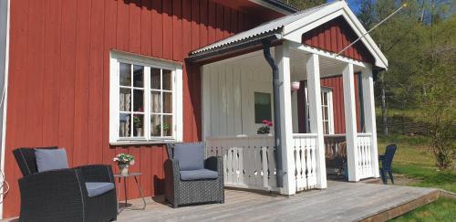 圖什比的住宿－Långtjärn 5, Torsby，红楼旁边的甲板上配有椅子的凉亭