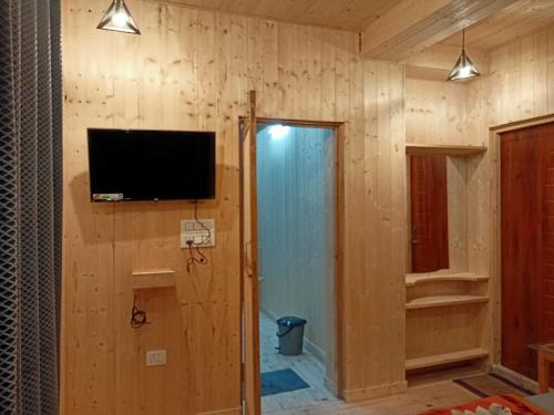 a room with a television on a wooden wall at THE GROOVE GARDEN DHANOLTi in Dhanaulti