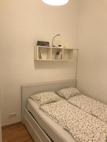a small bedroom with a bed with a shelf on the wall at Nice apartment near Schönbrunn and downtown in Vienna