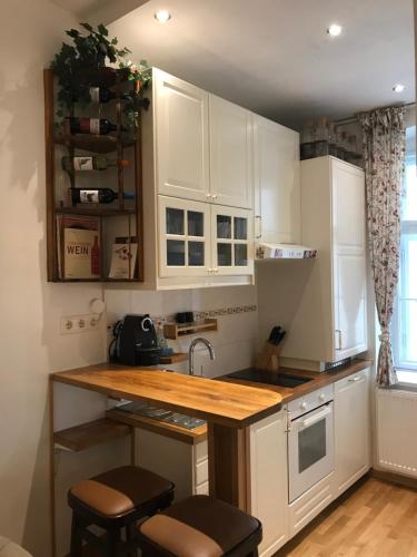 a kitchen with white cabinets and a wooden counter top at Nice apartment near Schönbrunn and downtown in Vienna