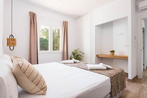 a white bedroom with two beds and a window at Villa Evita in Santo Tomás