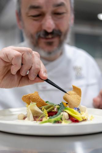 a man eating a plate of food with a fork and knife at Il Borro Relais & Châteaux in San Giustino Valdarno