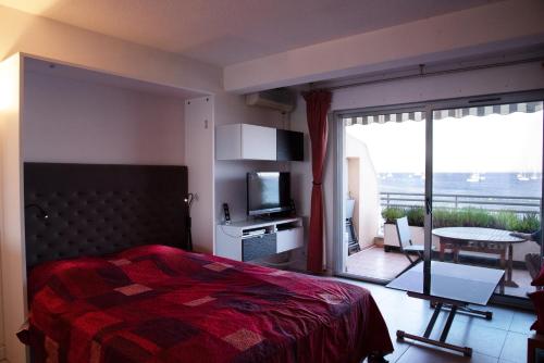 イエールにあるRésidence Bona vue mer panoramiqueのベッドルーム(ベッド1台、テレビ、バルコニー付)