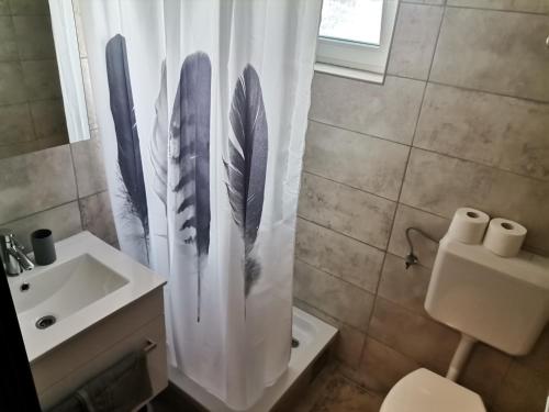 a bathroom with a shower curtain with feathers on it at Marin in Lopar