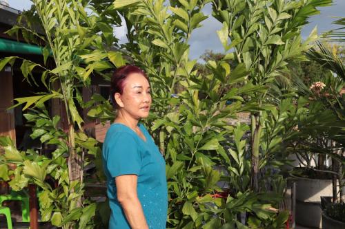a woman in a blue shirt standing in front of plants at Ban Sulada Guest House in Laem Ngop