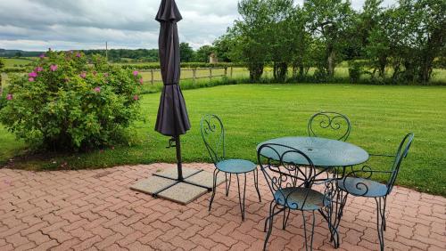 a table and chairs and an umbrella on a patio at Gite Le Morvan in Lormes