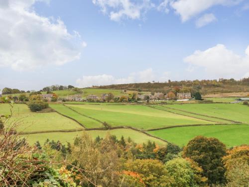 a green field with trees and houses in the distance at Bronte Barn in Keighley