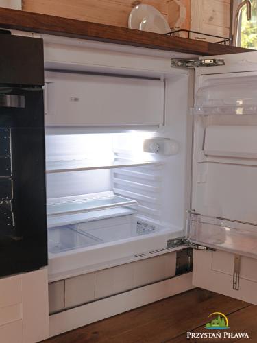 an empty refrigerator with its door open in a kitchen at Przystań Piława in Borne Sulinowo