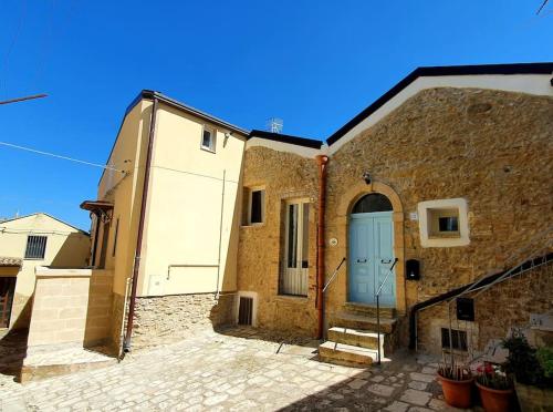 a brick building with a blue door and stairs at Casa Santa Maria - Beautifully restored house in centro storico Irsina Basilicata Puglia in Irsina
