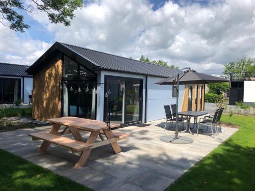 a picnic table and an umbrella on a patio at Luxe en gezellig chalet aan Veluwemeer 4 pers in Hulshorst