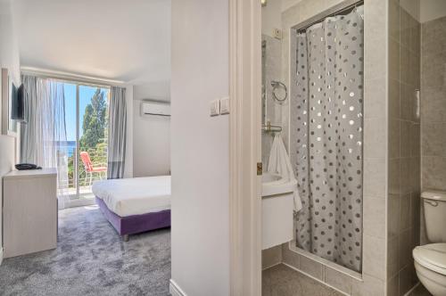 a bathroom with a shower and a toilet and a bed at Hotel Aqua - Guest Rooms & Suites Kaštela in Kaštela