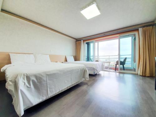 a hotel room with two beds and a large window at Jeju Ocean Family Hotel in Jeju