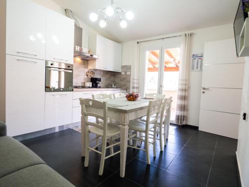 a kitchen with white cabinets and a table and chairs at SweetHome - MORADA in Torpè