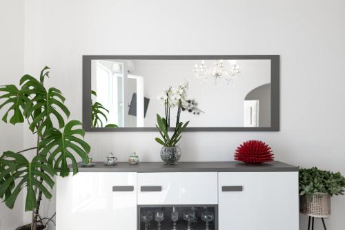 a mirror in a white room with flowers on a counter at Casa Clara in Praiano