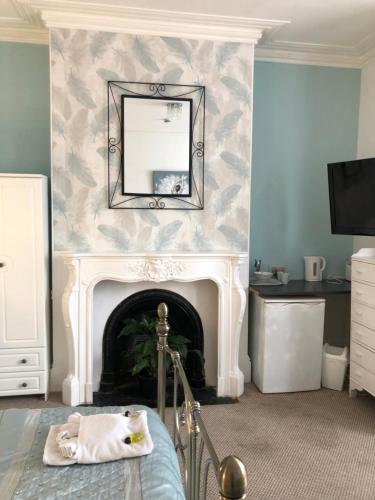 a bedroom with a fireplace with a mirror and a bed at The Mayfair Hotel in Great Yarmouth