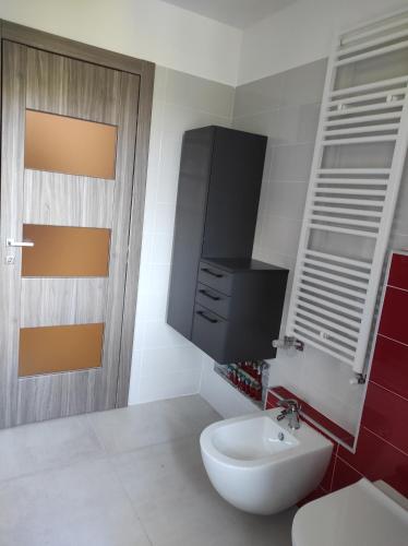 La salle de bains est pourvue d'un lavabo blanc et d'une armoire rouge. dans l'établissement Oasi del Monferrato - appartamento rosso, à Mombercelli