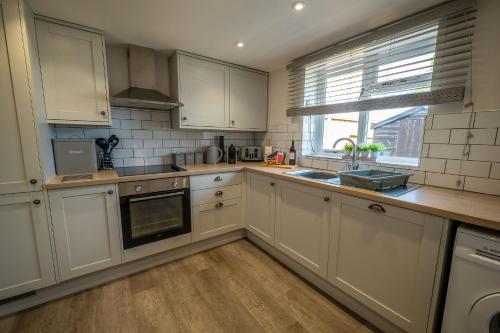 a kitchen with white cabinets and a sink and a window at The Stables in Halesworth