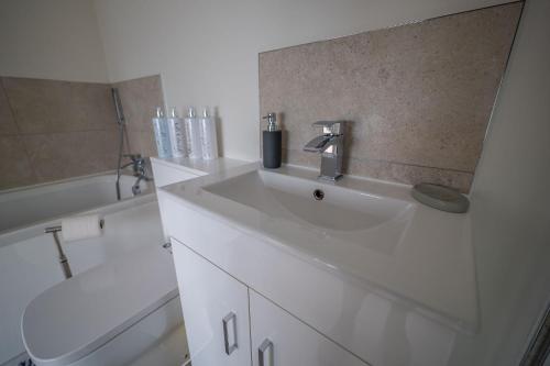 a white bathroom with a sink and a toilet at The Stables in Halesworth