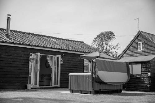 a house with a pool and an umbrella in front of it at The Stables in Halesworth
