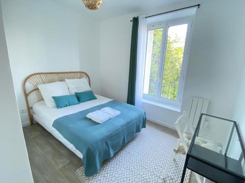 a bedroom with a bed with blue sheets and a window at Appartement Gare de Meaux - Proche Disney /Paris in Meaux