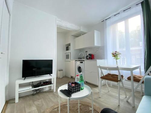 a white living room with a tv and a table at Appartement Gare de Meaux - Proche Disney /Paris in Meaux