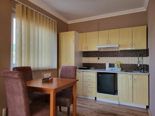 une cuisine avec des armoires jaunes, une table et des chaises dans l'établissement Sun and river Apartments, à Golubac