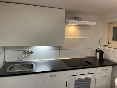 una cucina con armadi bianchi e lavandino di Detmold - Hiddesen - Premium - Appartement a Detmold